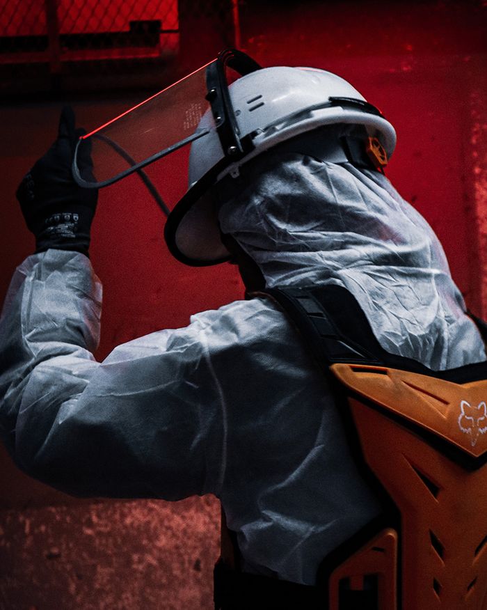 team-03 Worker in protective clothing and helmet at a construction site lit in red tones.