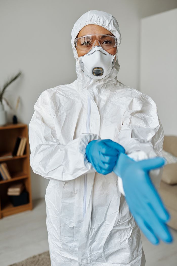 Healthcare worker wearing PPE, including mask and gloves, indoors for safety.